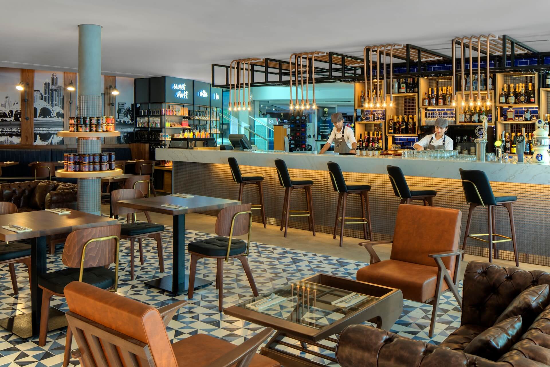 Modern bar and lounge with wooden furniture, turquoise column, geometric floor, and backlit shelving