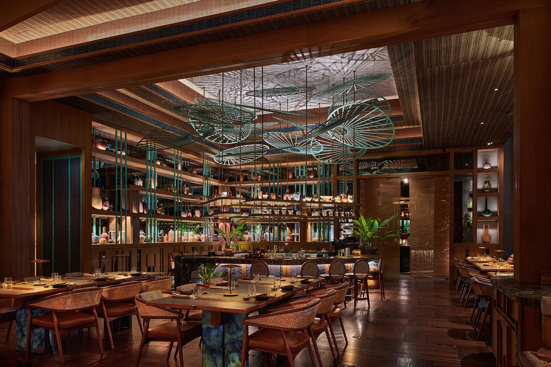 Modern upscale restaurant interior with wooden furniture, turquoise accents, and artistic ceiling sculptures