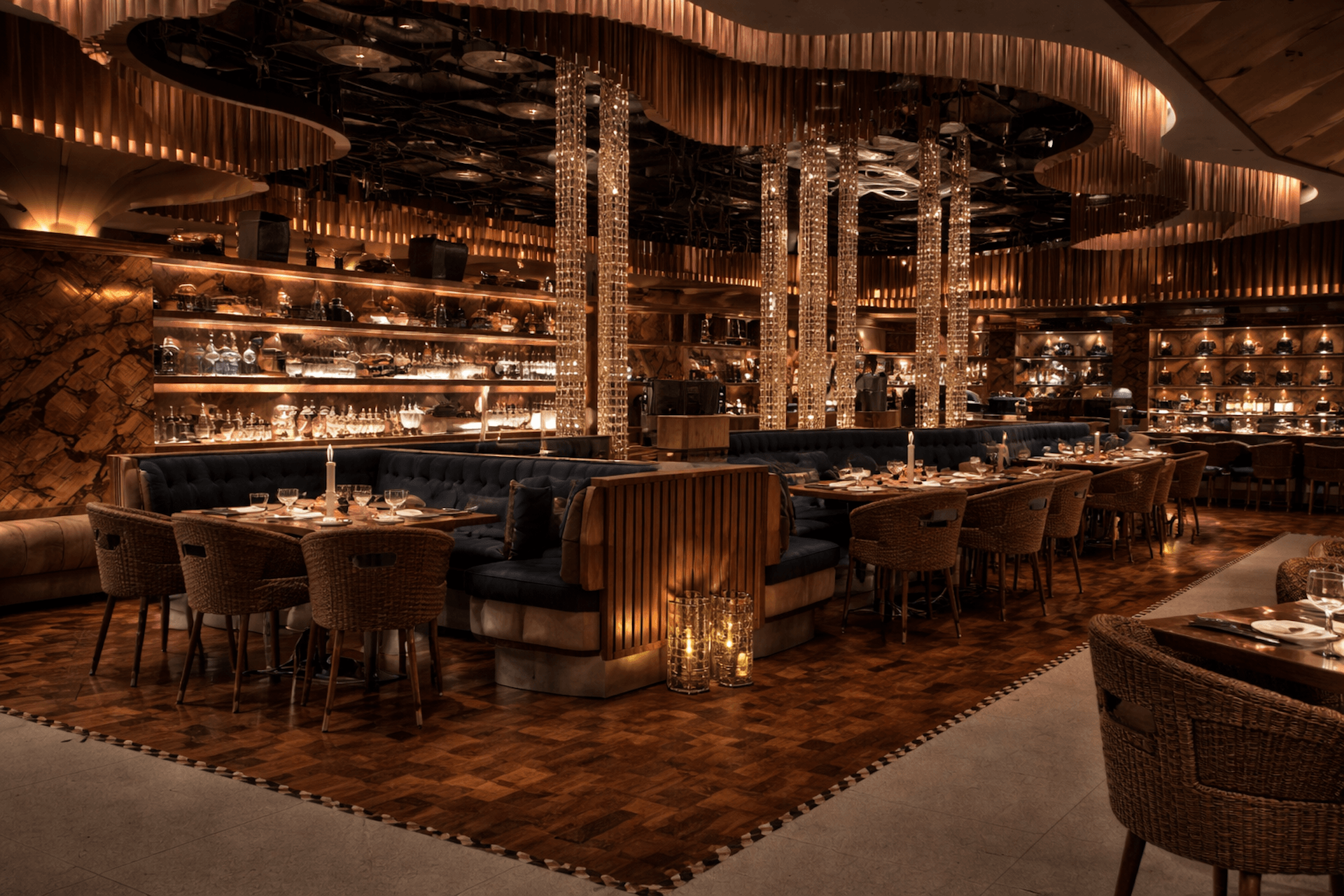 Luxurious restaurant interior with crystal chandeliers, black booths, and warm golden lighting