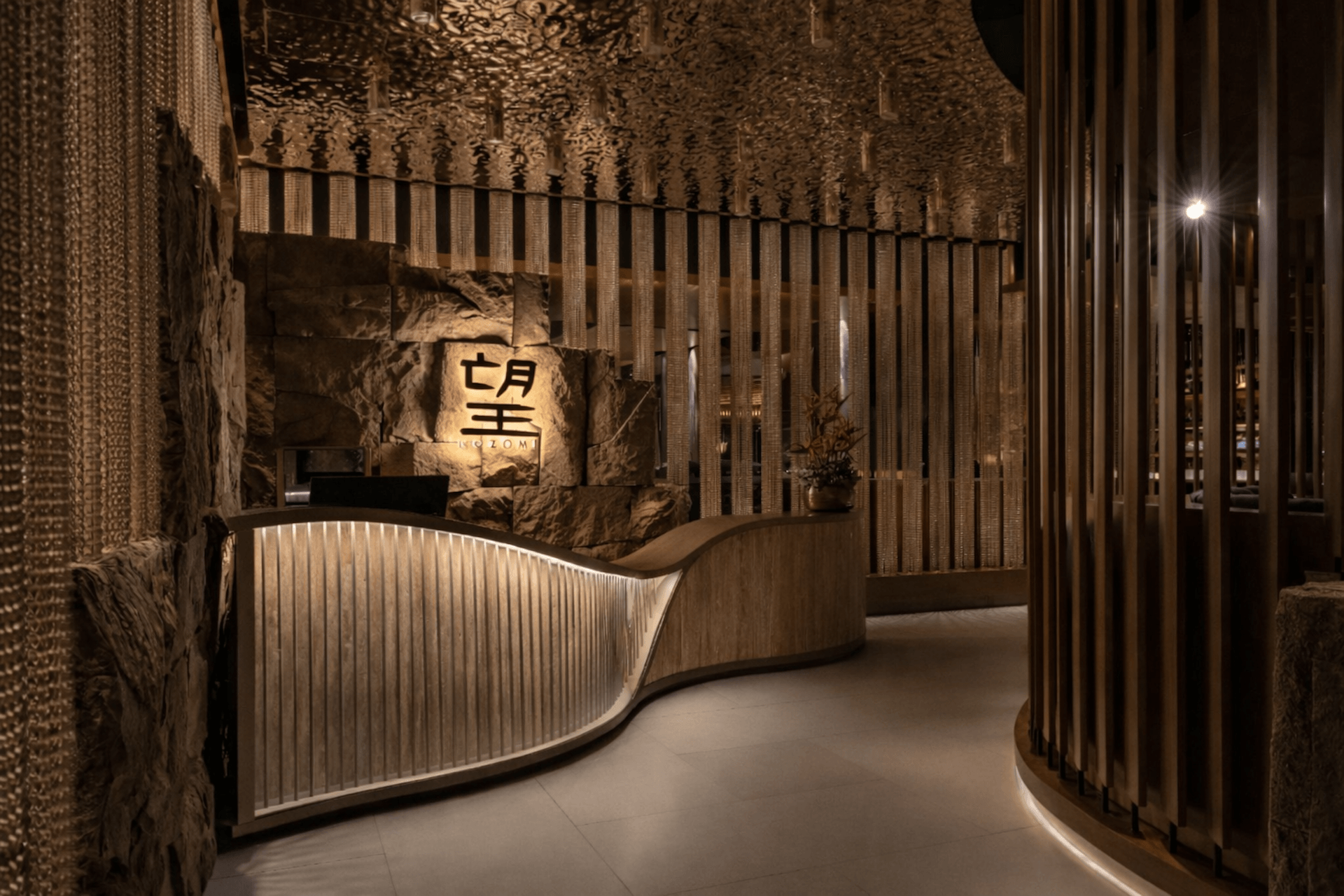 Modern Asian restaurant entrance with illuminated curved counter and Japanese signage at night