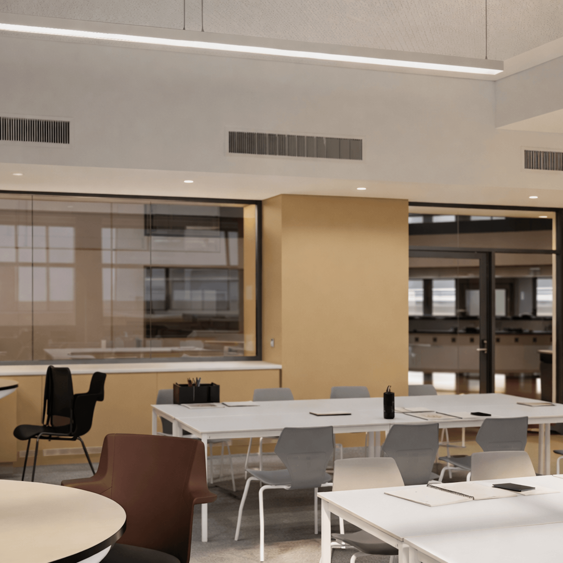 Modern office interior with white tables, gray chairs, glass partitions, and contemporary lighting fixtures.
