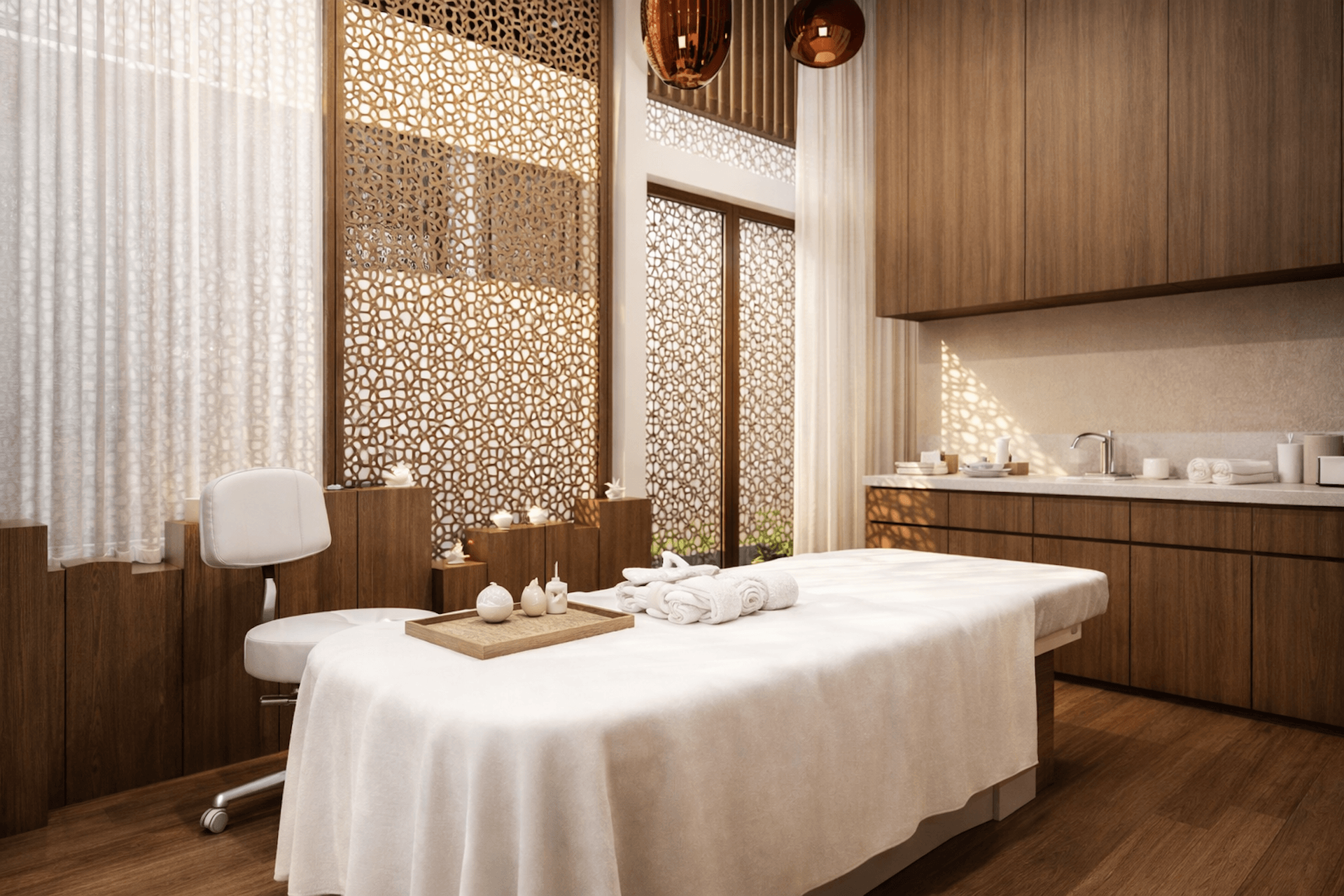 Spa massage room with white draped table, decorative wooden screens, and modern wellness furnishings.