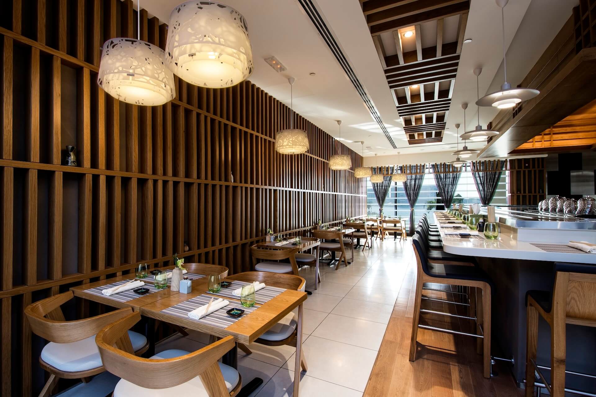 Modern restaurant interior with wooden slat walls, pendant lights, and dining tables