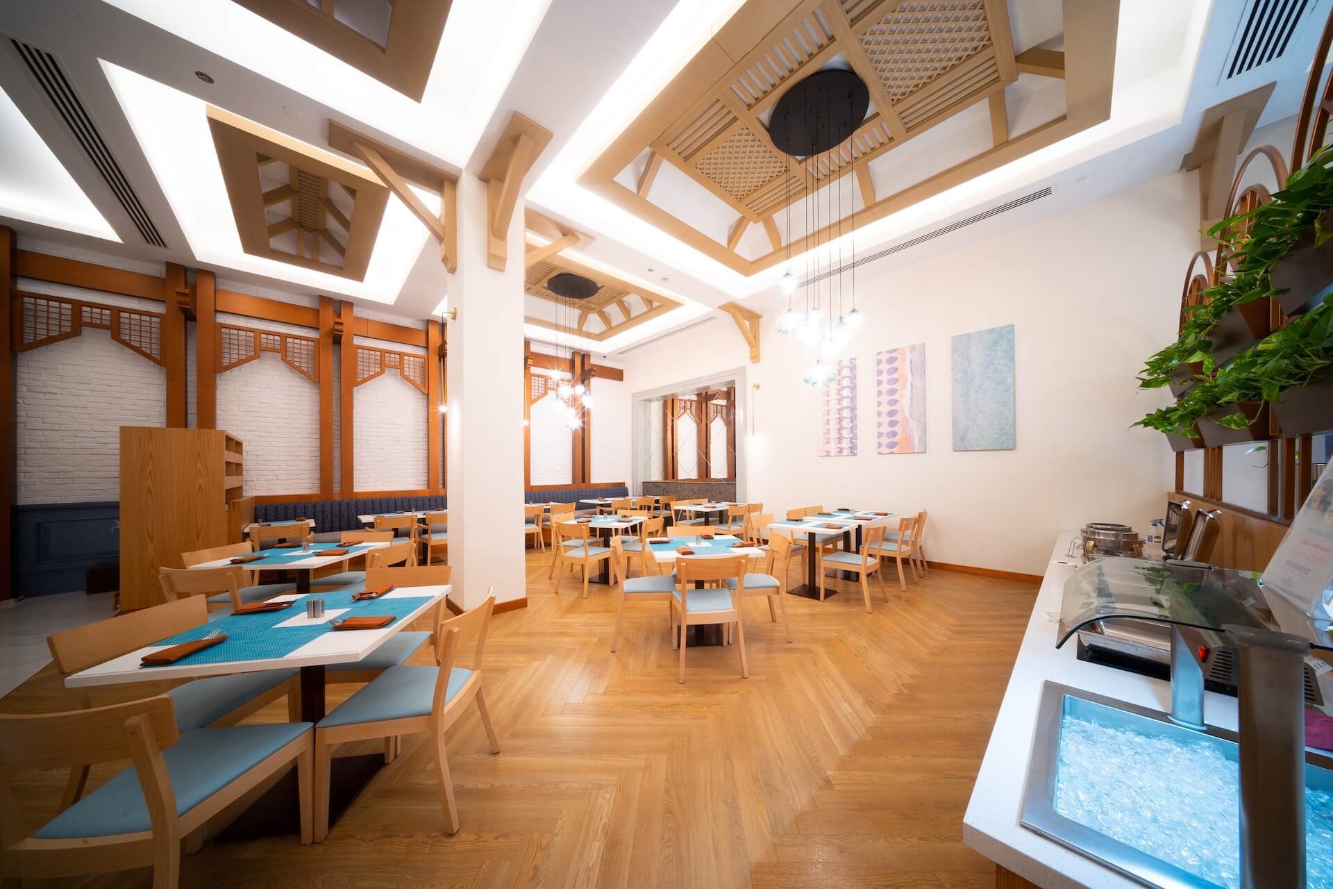 Modern restaurant interior with wooden tables, chairs, and architectural ceiling design