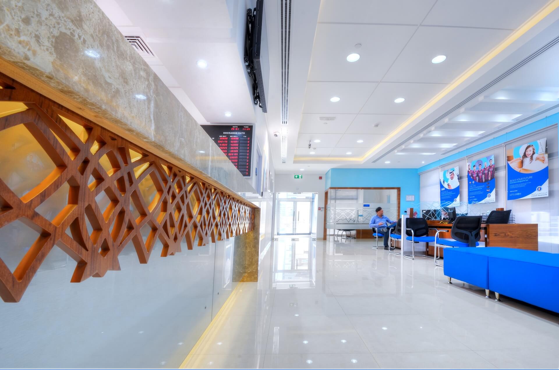 Modern office lobby with blue seating, wooden decorative panels, and reception desk.