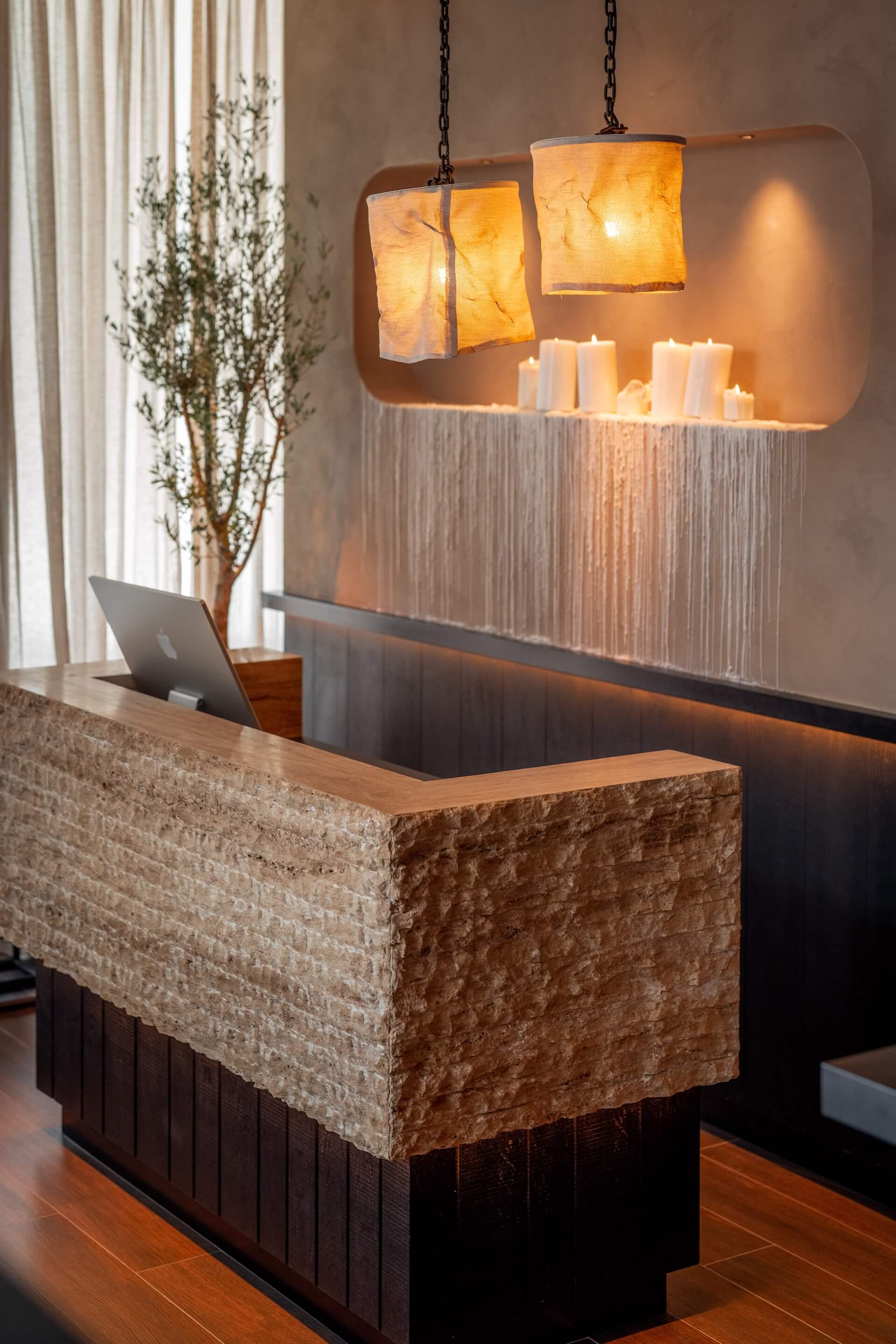 Modern hotel reception desk with hanging amber pendant lights and candles