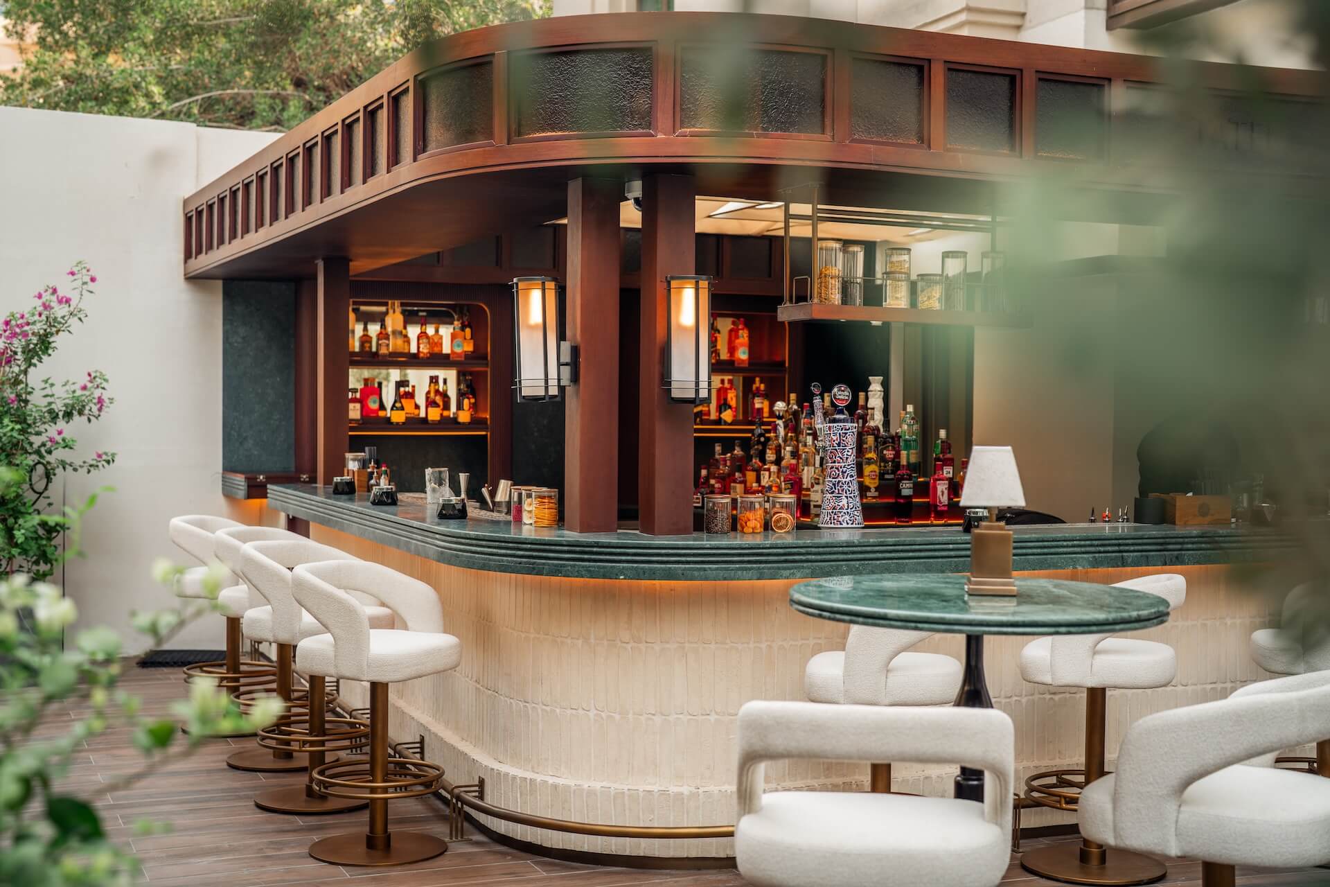 Modern curved bar counter with cream seating, stocked liquor shelves, and wood accents