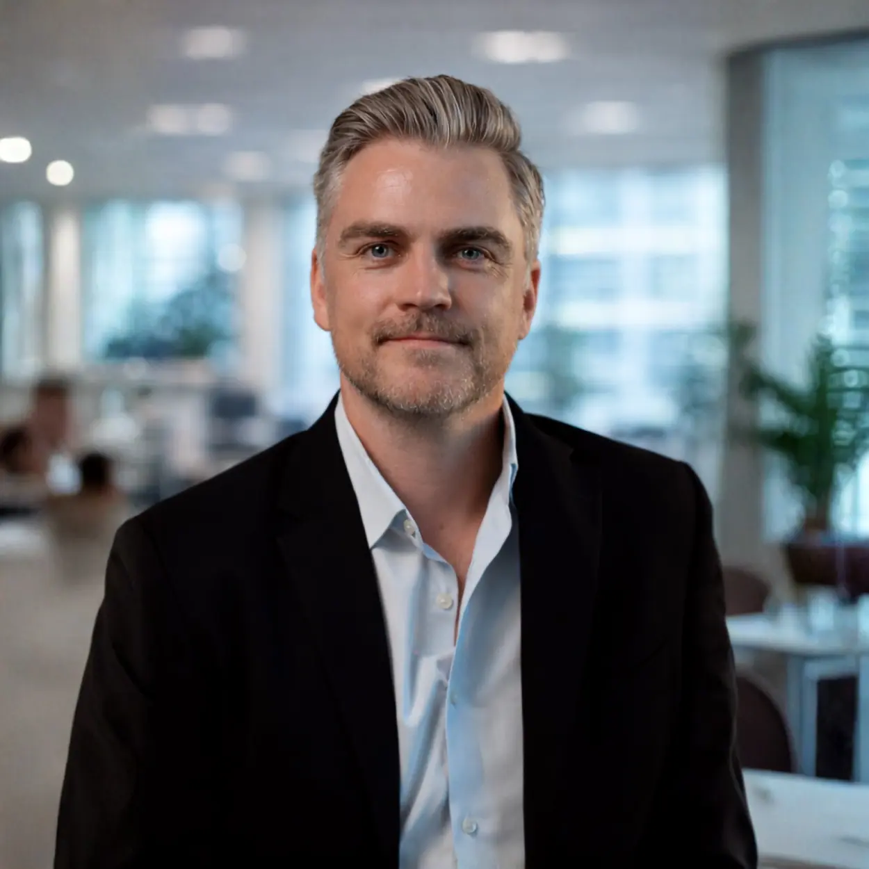 Professional man in black blazer and light blue shirt in modern office setting