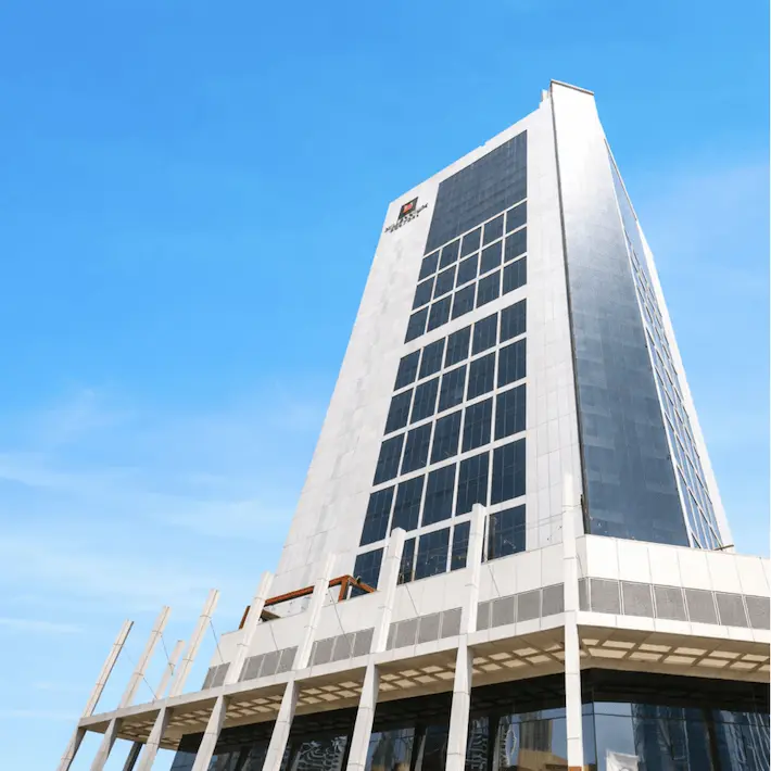 Tall modern office building with white and gray facade against blue sky