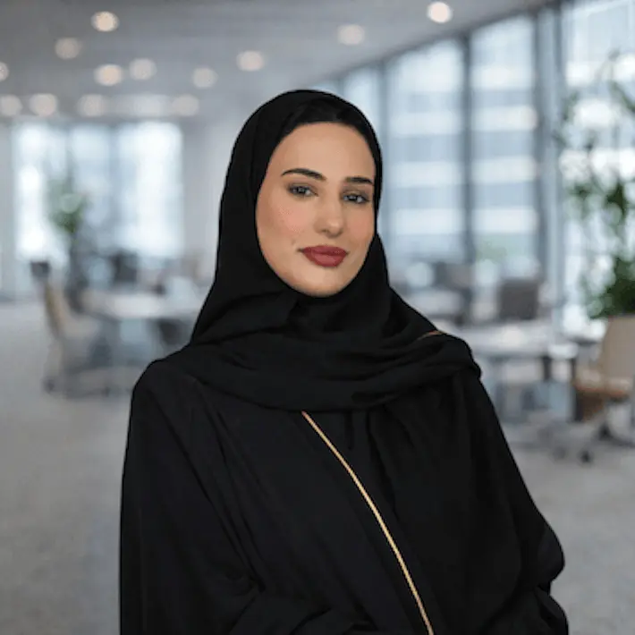 Woman wearing black hijab and abaya in modern office environment with windows