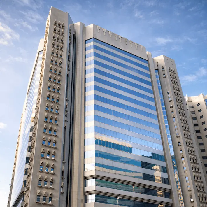 Modern high-rise office building with blue striped facade surrounded by beige residential towers