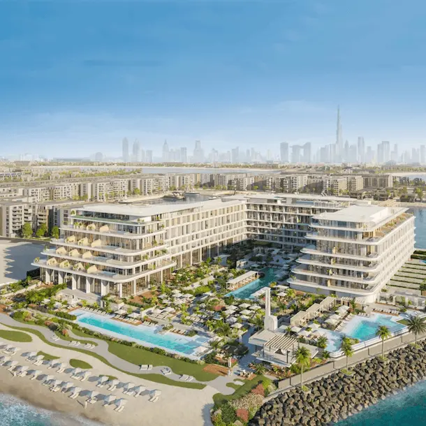 Modern beachfront resort with curved architecture, pools, and landscaped grounds overlooking Dubai skyline.