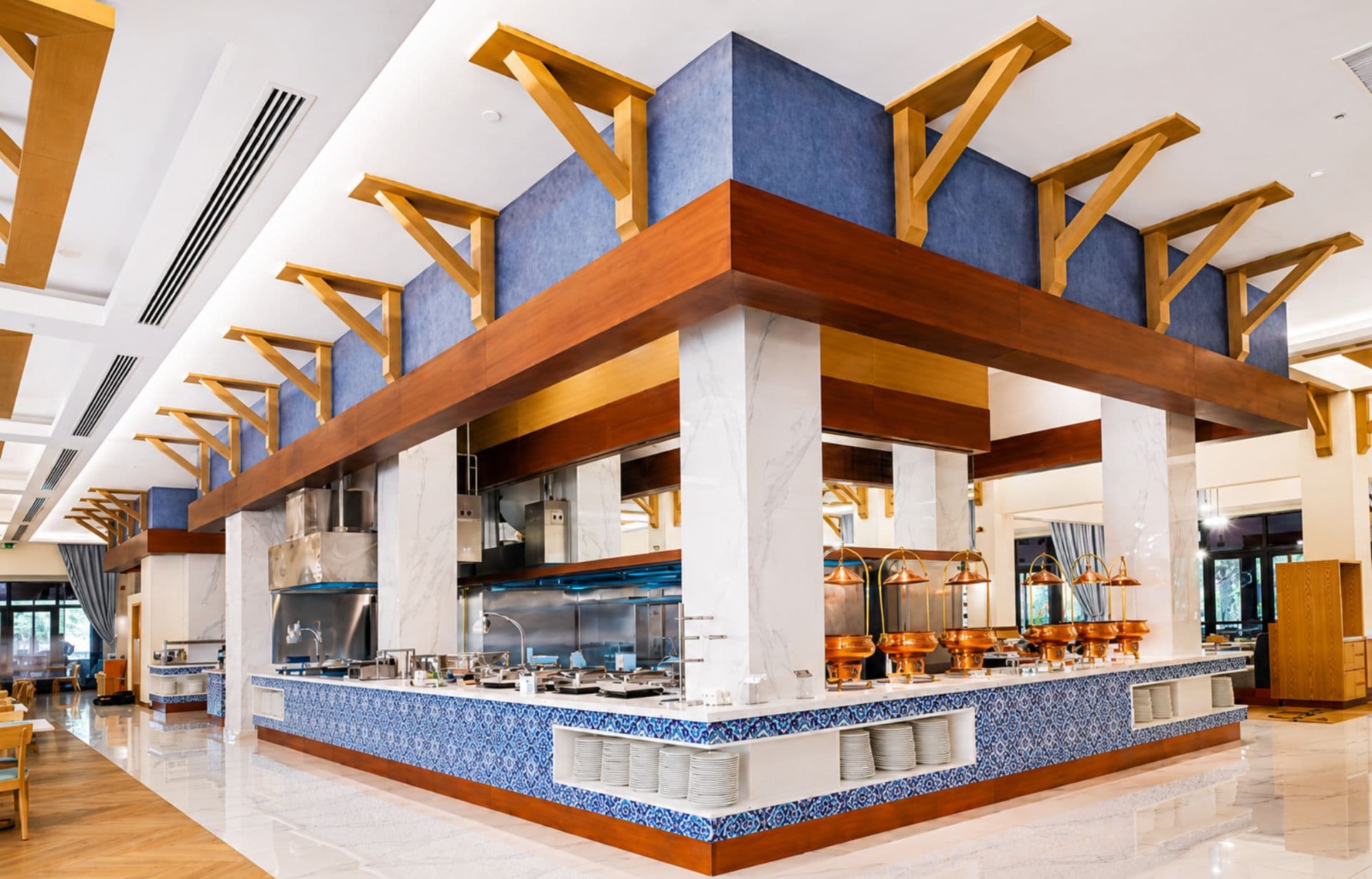 Modern restaurant kitchen with wooden beams, blue accent tiles, and stainless steel cooking station