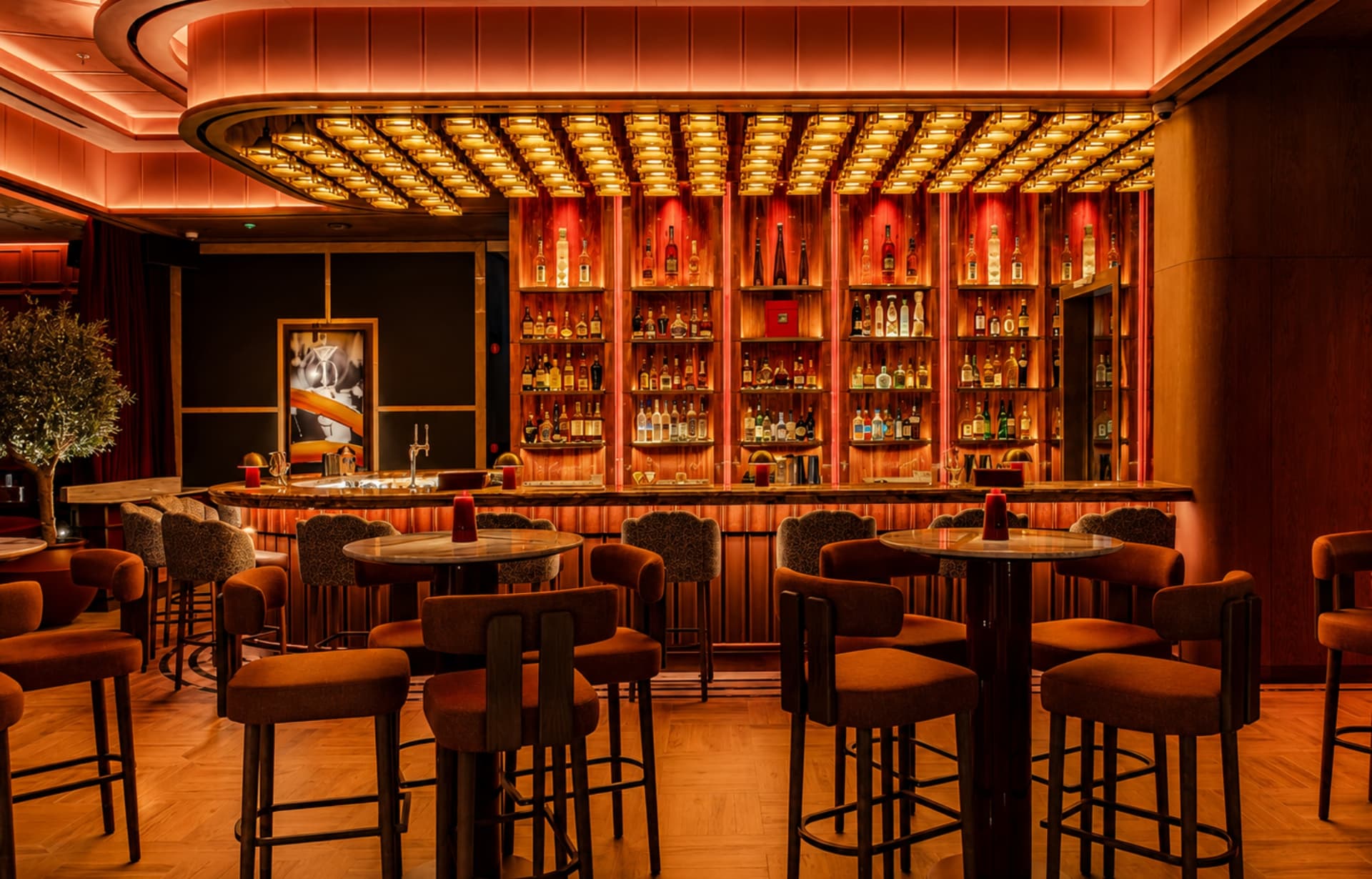 Upscale bar lounge with warm amber lighting, wooden bar counter, extensive liquor shelves, and modern seating.