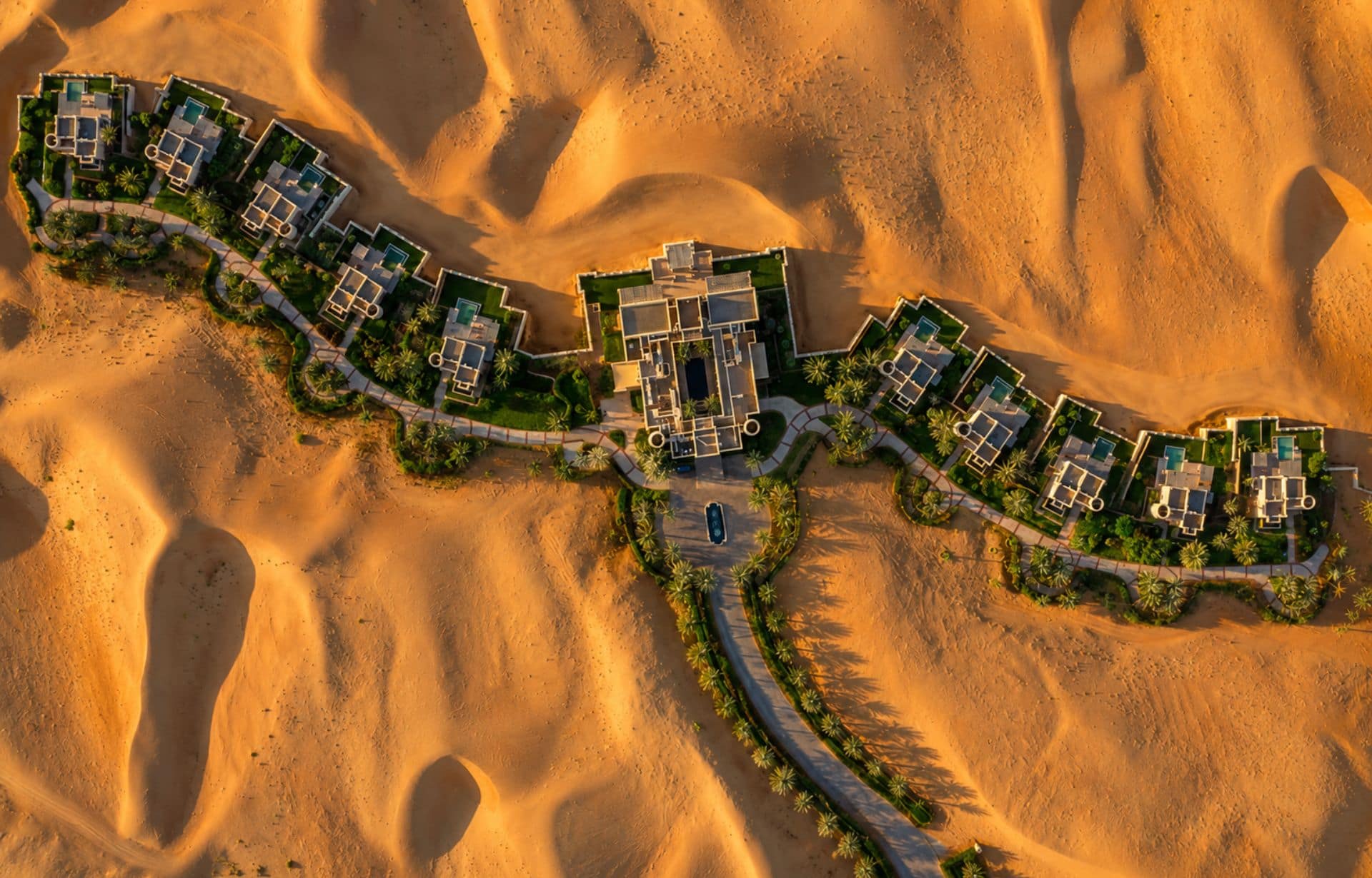 Aerial view of luxury resort compound with villas in vast desert dunes landscape
