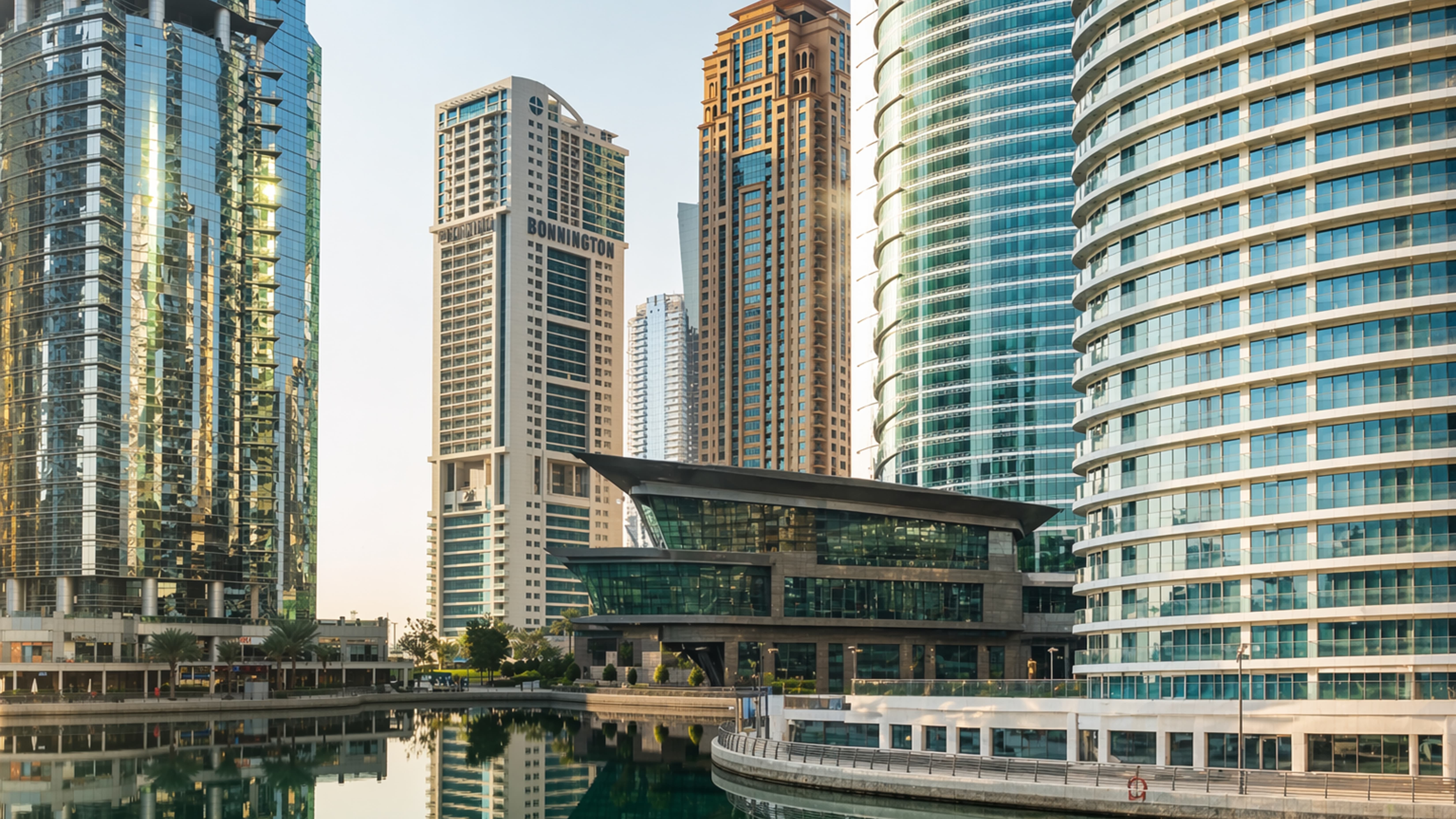 Modern skyscrapers reflecting in canal water with contemporary curved glass building in center.