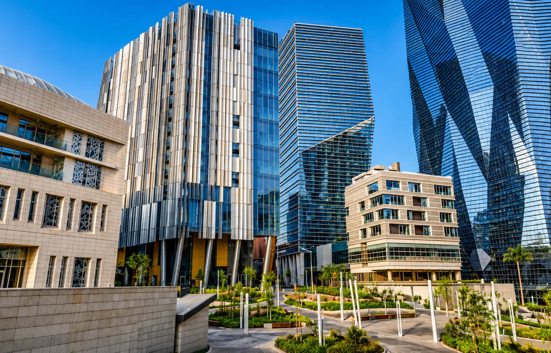 Modern urban plaza with mixed architectural styles and residential towers under blue sky