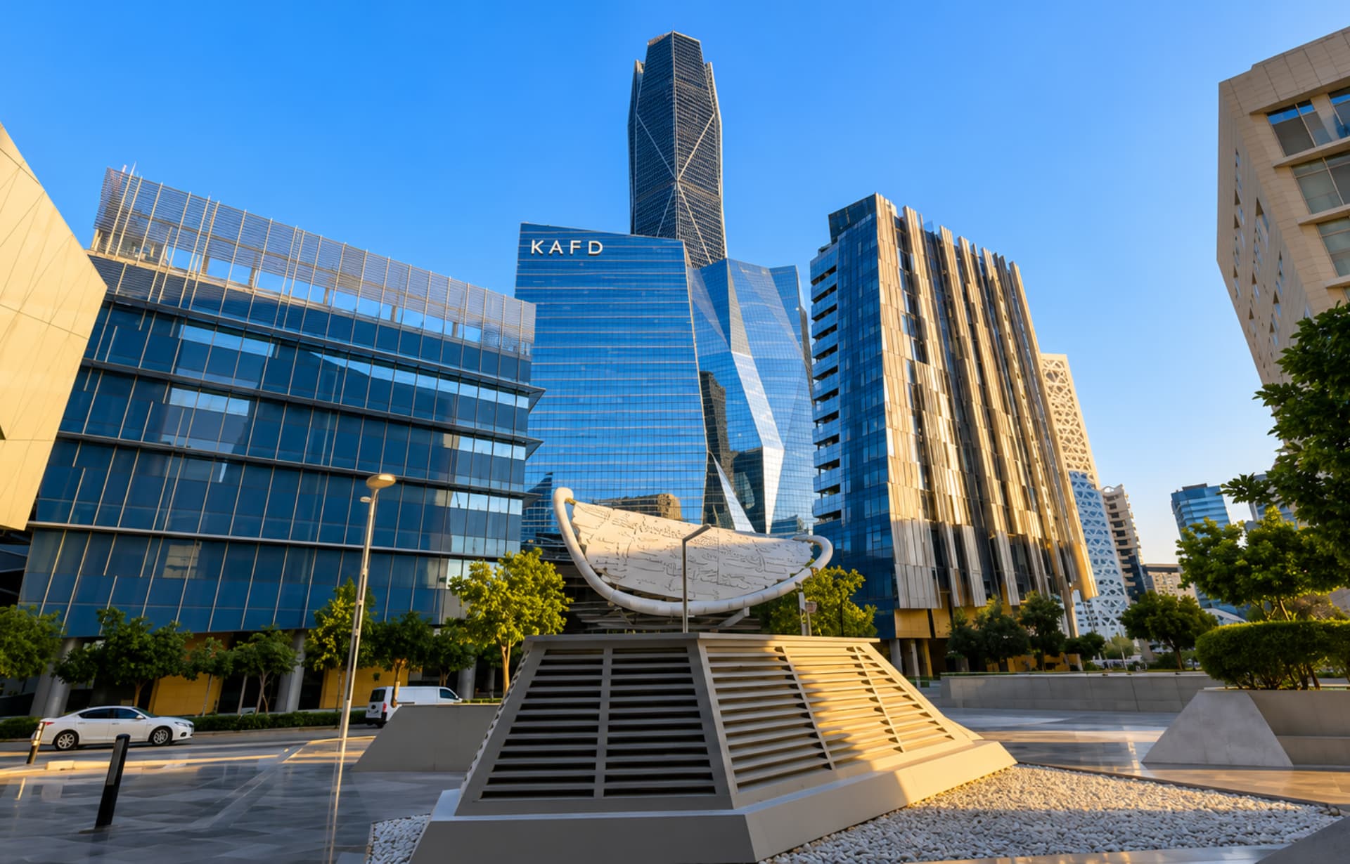Modern downtown cityscape with KAFD tower, curved architecture, sculpture, and contemporary buildings under blue sky