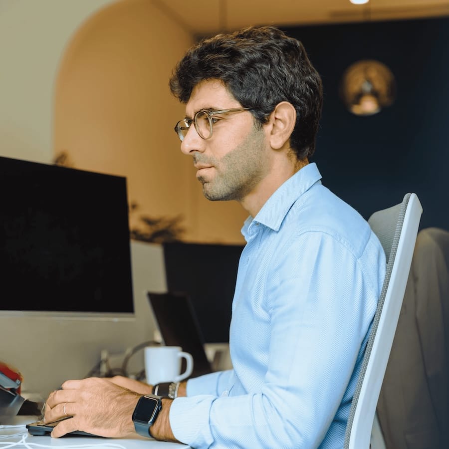 Man with glasses working at desk with computer and coffee mug