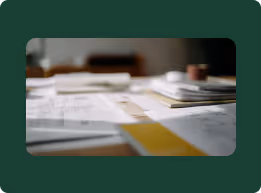 Blurred close-up of architectural plans and documents spread on a table.