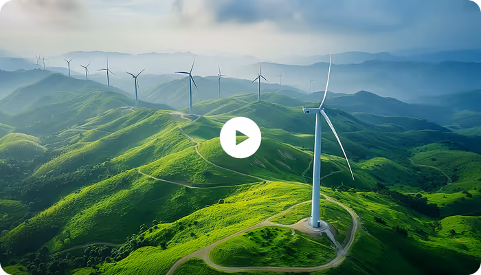Aerial view of green rolling hills with multiple wind turbines generating clean energy under a cloudy sky.
