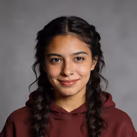 Young woman with braided hair wearing a maroon hoodie, smiling at the camera against a plain gray background.
