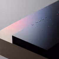 Close-up of a sleek black device corner with touch-sensitive controls and small LED indicator lights.