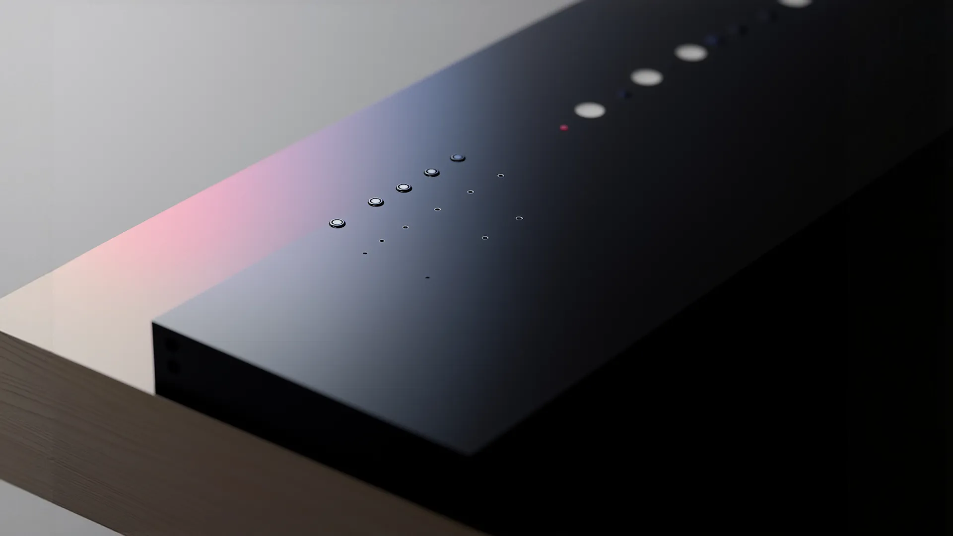 Close-up of a sleek black electronic device with circular buttons and a wooden surface base.