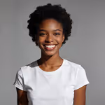 Smiling young Black woman with short curly hair wearing a white t-shirt against a gray background.