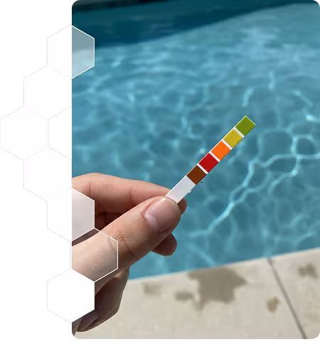 Main tenant une bandelette de test de pH avec une piscine en arrière-plan.