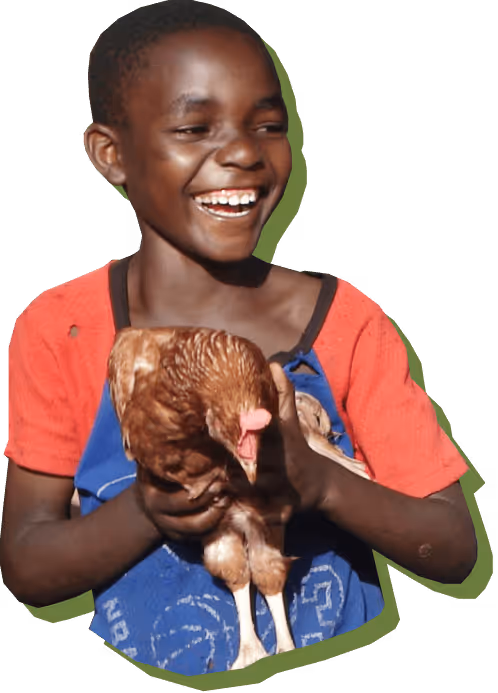 Lachender Junge hält ein braunes Huhn im Arm.