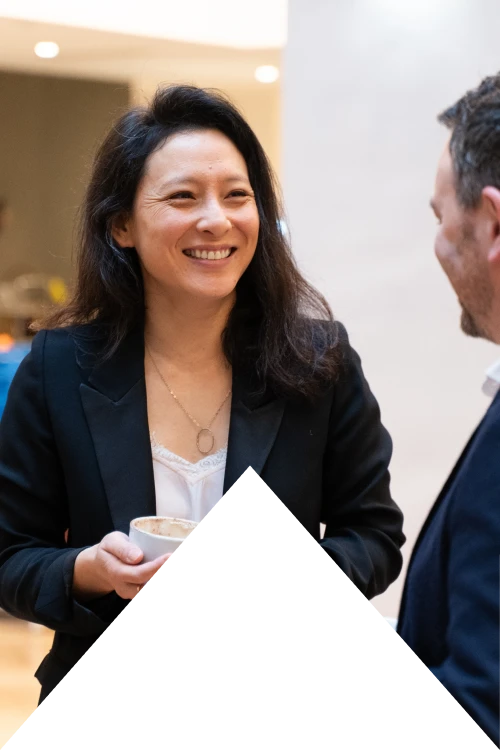 Femme souriante tenant une tasse de café lors d'une conversation avec un homme.