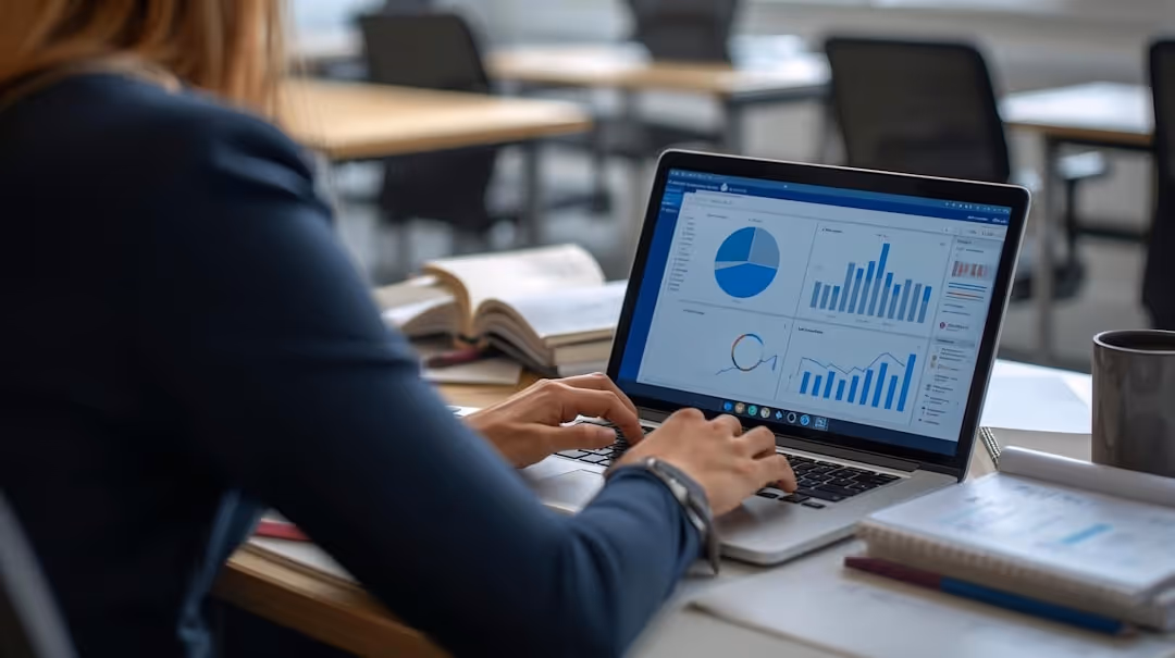 Person working on a laptop displaying charts and graphs with books and a cup on the desk.