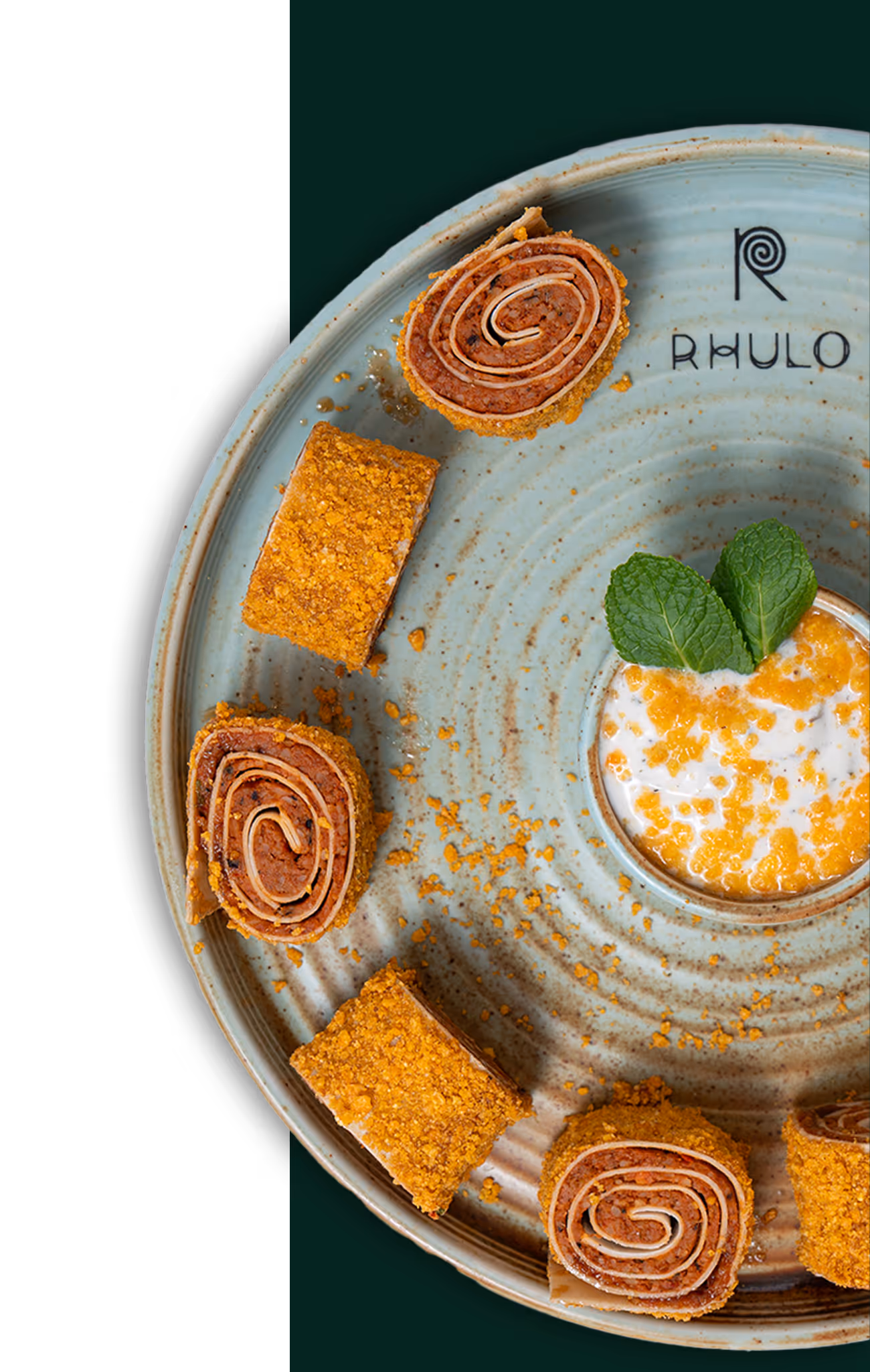 Runde Platte mit sechs goldbraun panierten, gerollten Snacks und einem Dip mit Minzblättern in der Mitte.