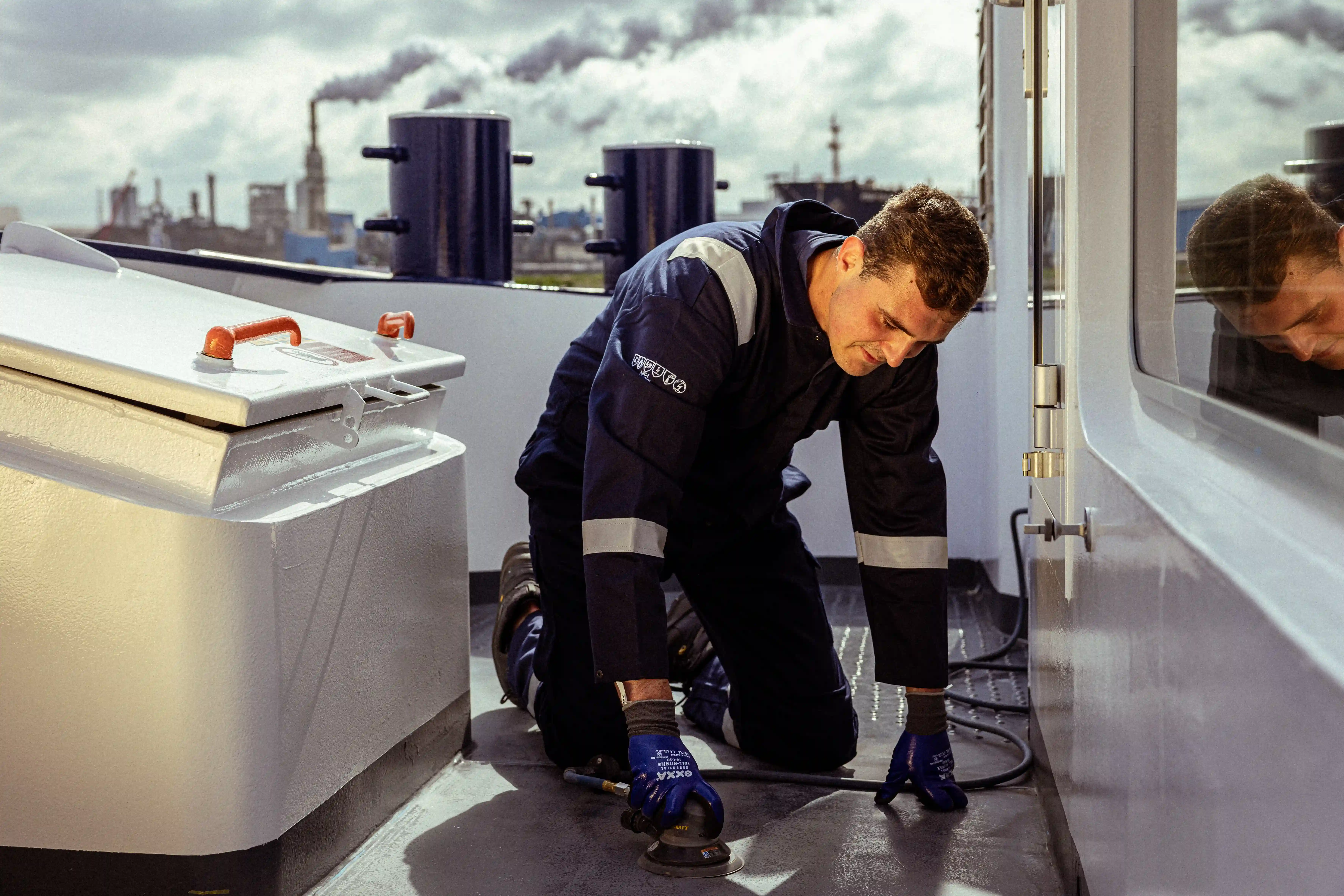 Bemanningslid voert dekwerkzaamheden en schuurwerk uit aan boord van een schip