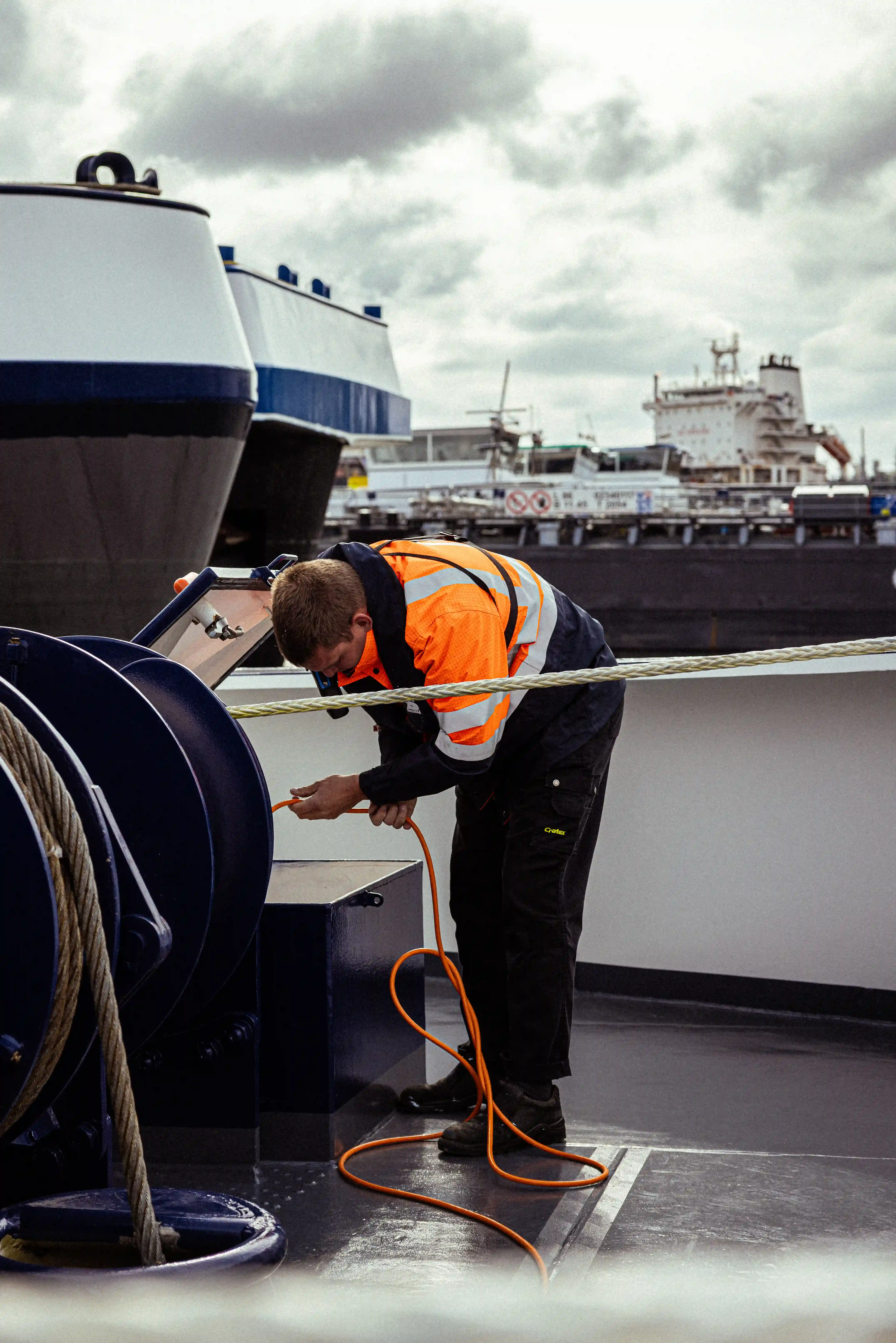 Een matroos van Mercurius in een reflecterende werkjas werkt met een kabel op het dek van een binnenschip