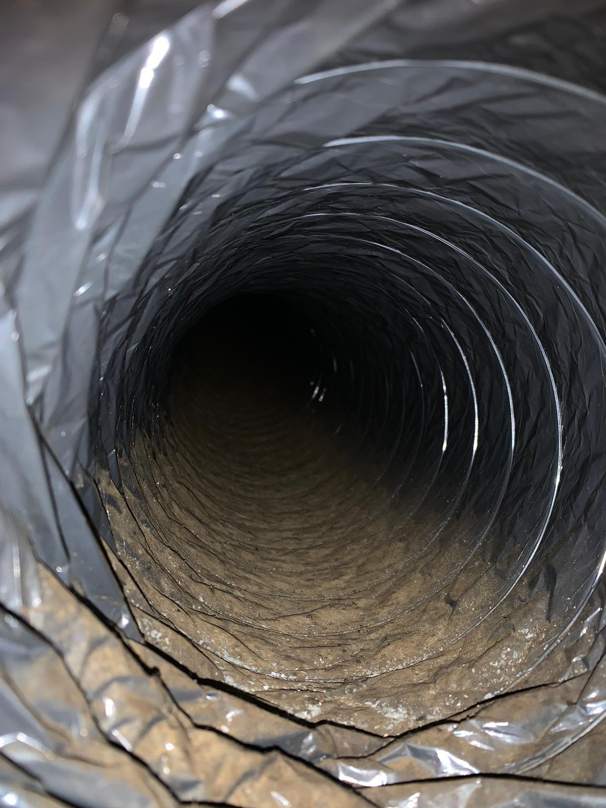 Inner view of a dirty ventilation duct covered with dust and debris.