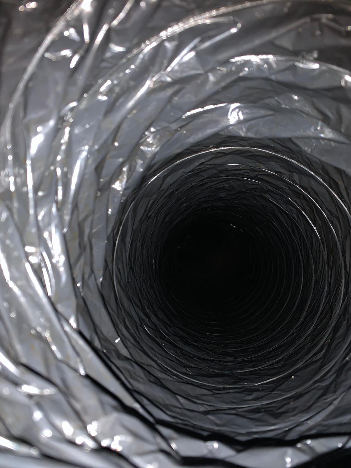 Inside view of a flexible black ventilation duct with metal duct and blade visible at the end.
