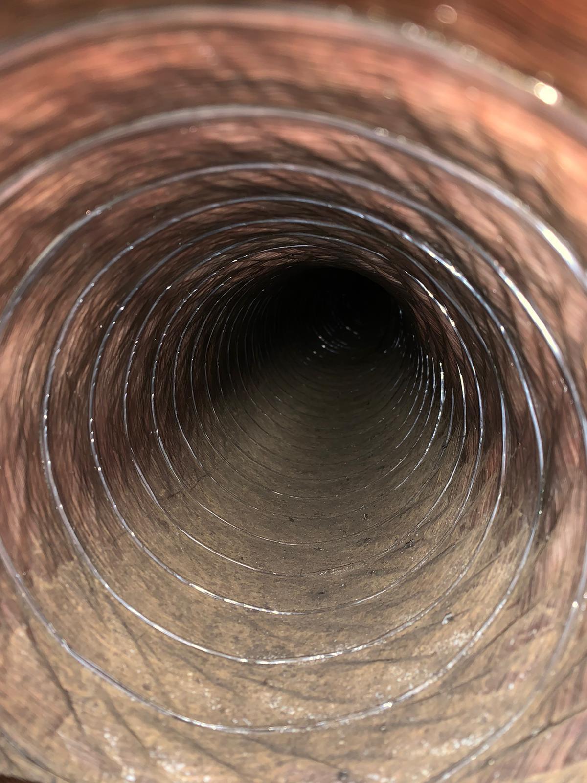 Inner view of a dirty ventilation duct covered with dust and debris.