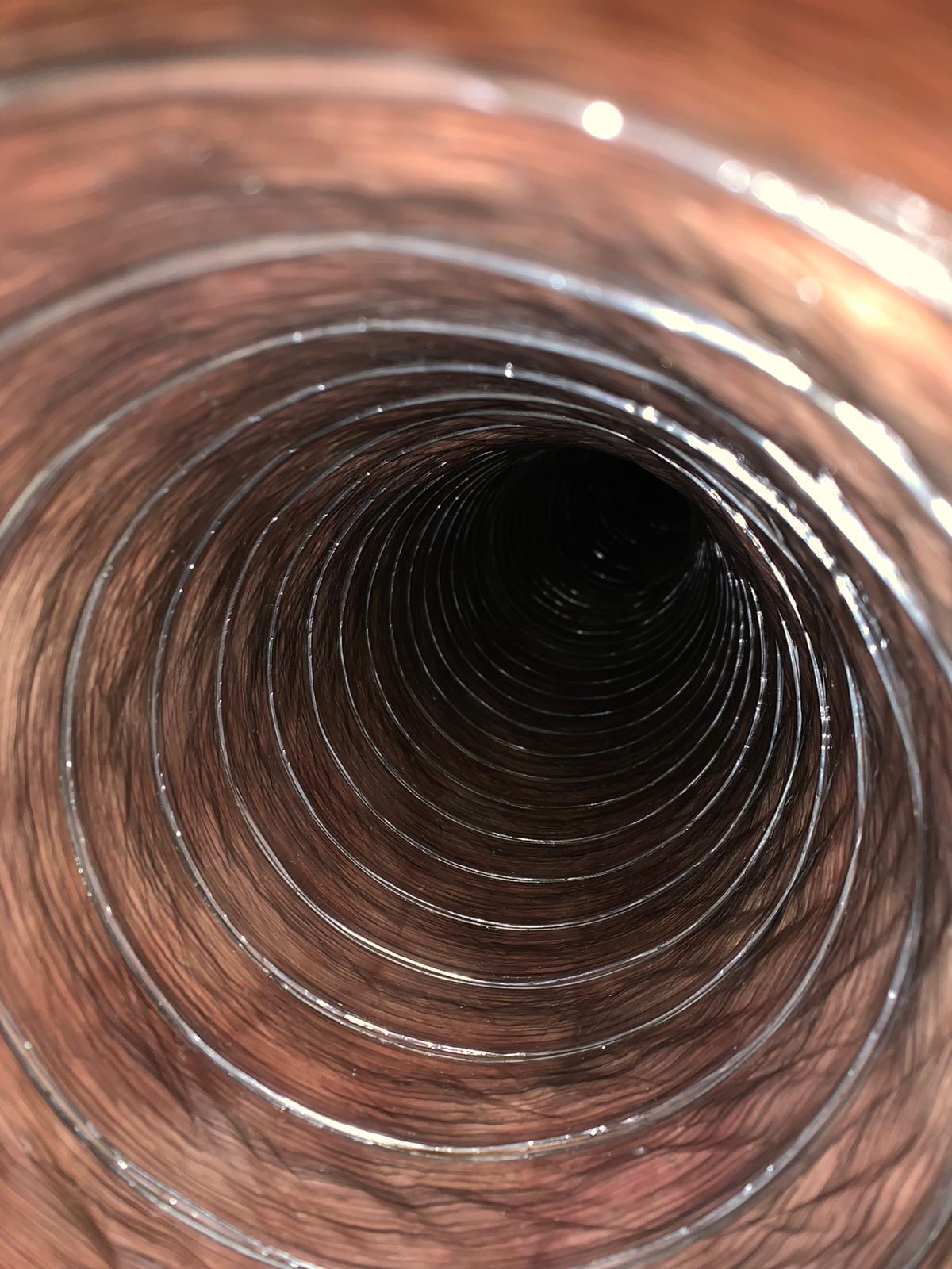 Inside view of a flexible black ventilation duct with metal duct and blade visible at the end.