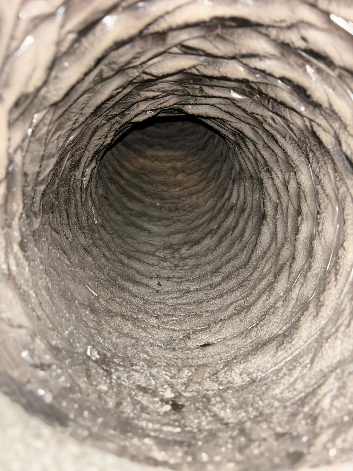 Inner view of a dirty ventilation duct covered with dust and debris.