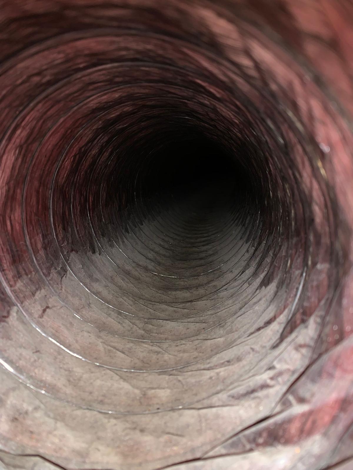 Inner view of a dirty ventilation duct covered with dust and debris.