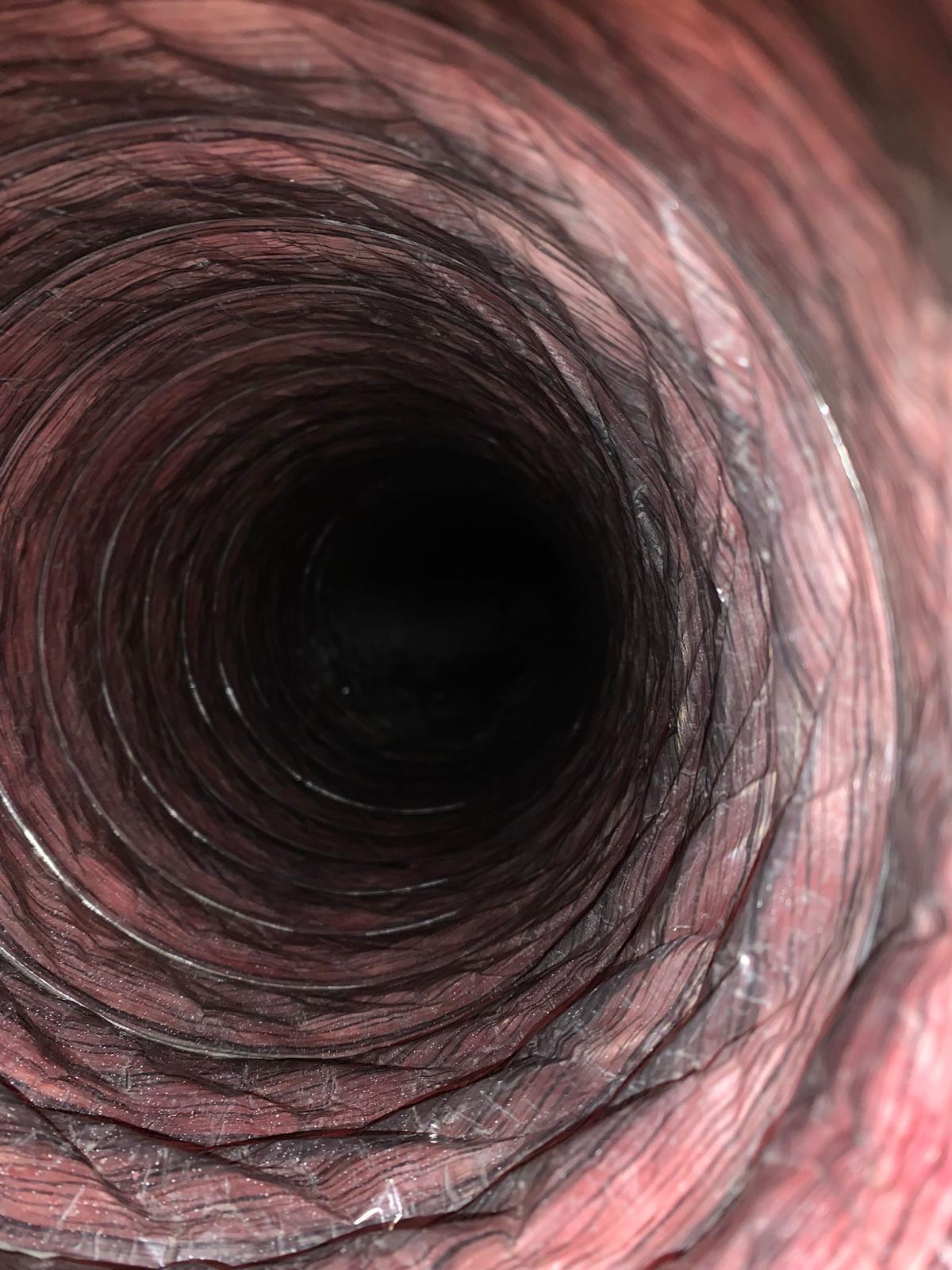 Inside view of a flexible black ventilation duct with metal duct and blade visible at the end.