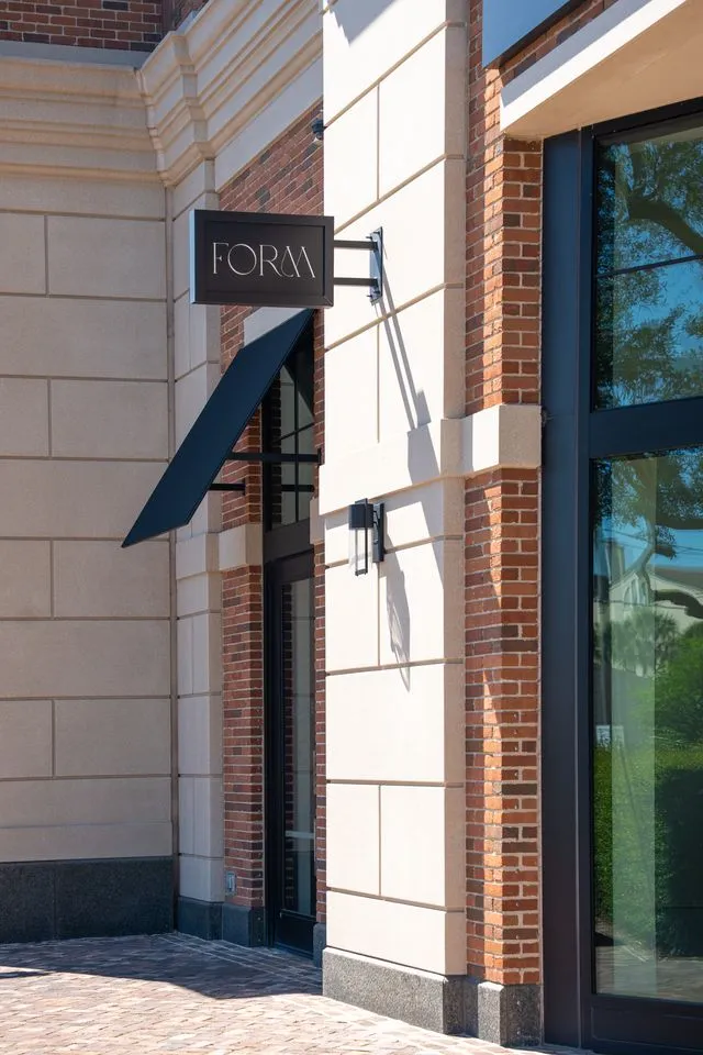 Storefront entrance with a black sign reading 'FORM' mounted on a beige and brick building.