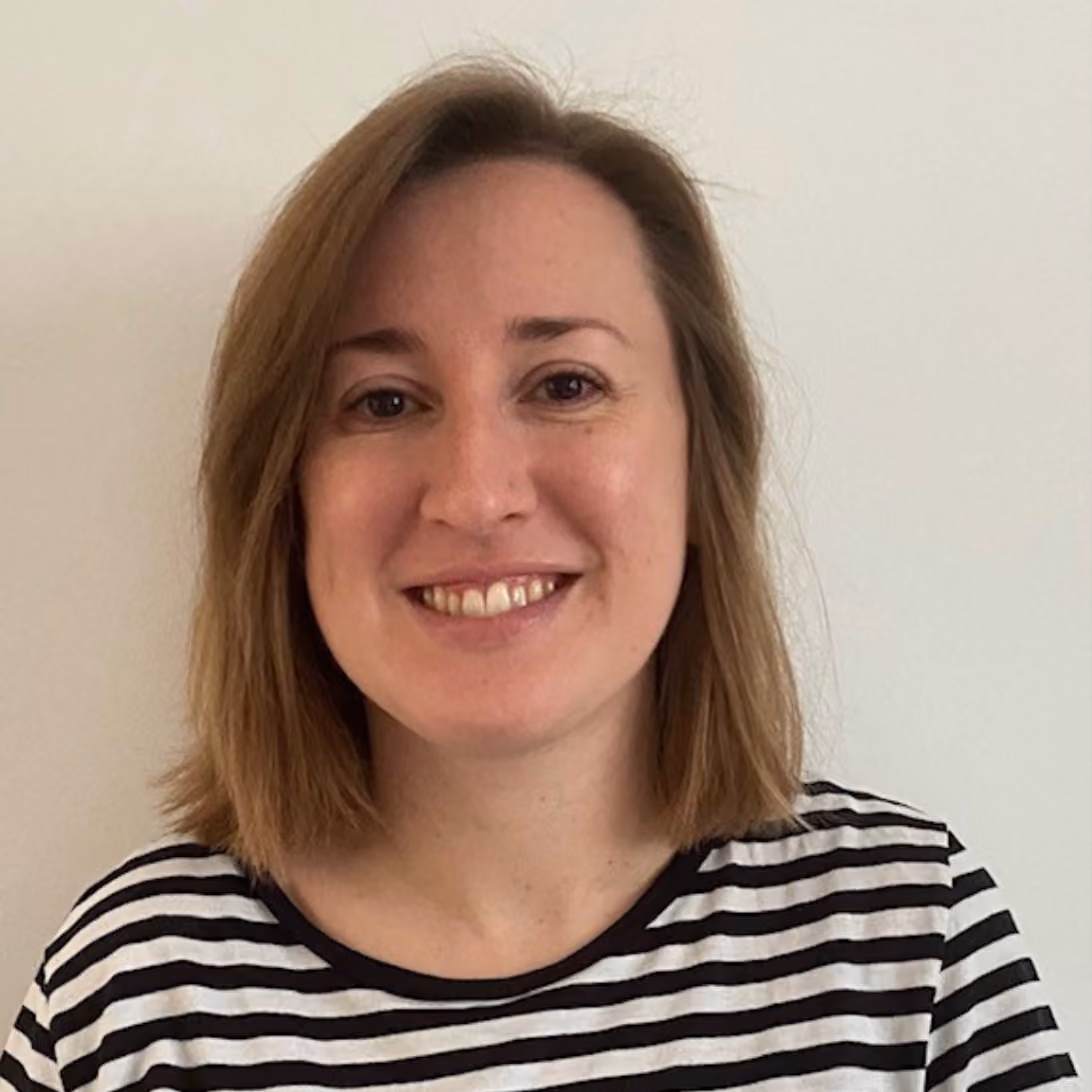 Woman with shoulder-length light brown hair smiling, wearing a black and white striped shirt.