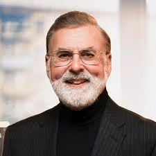 Smiling woman with curly blonde hair and blue eyes wearing a black top.