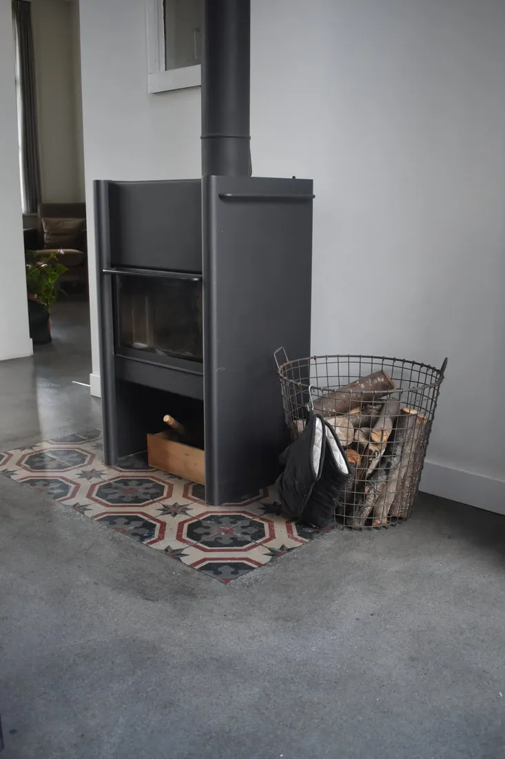 Beton leefvloer met open haard en tegels.