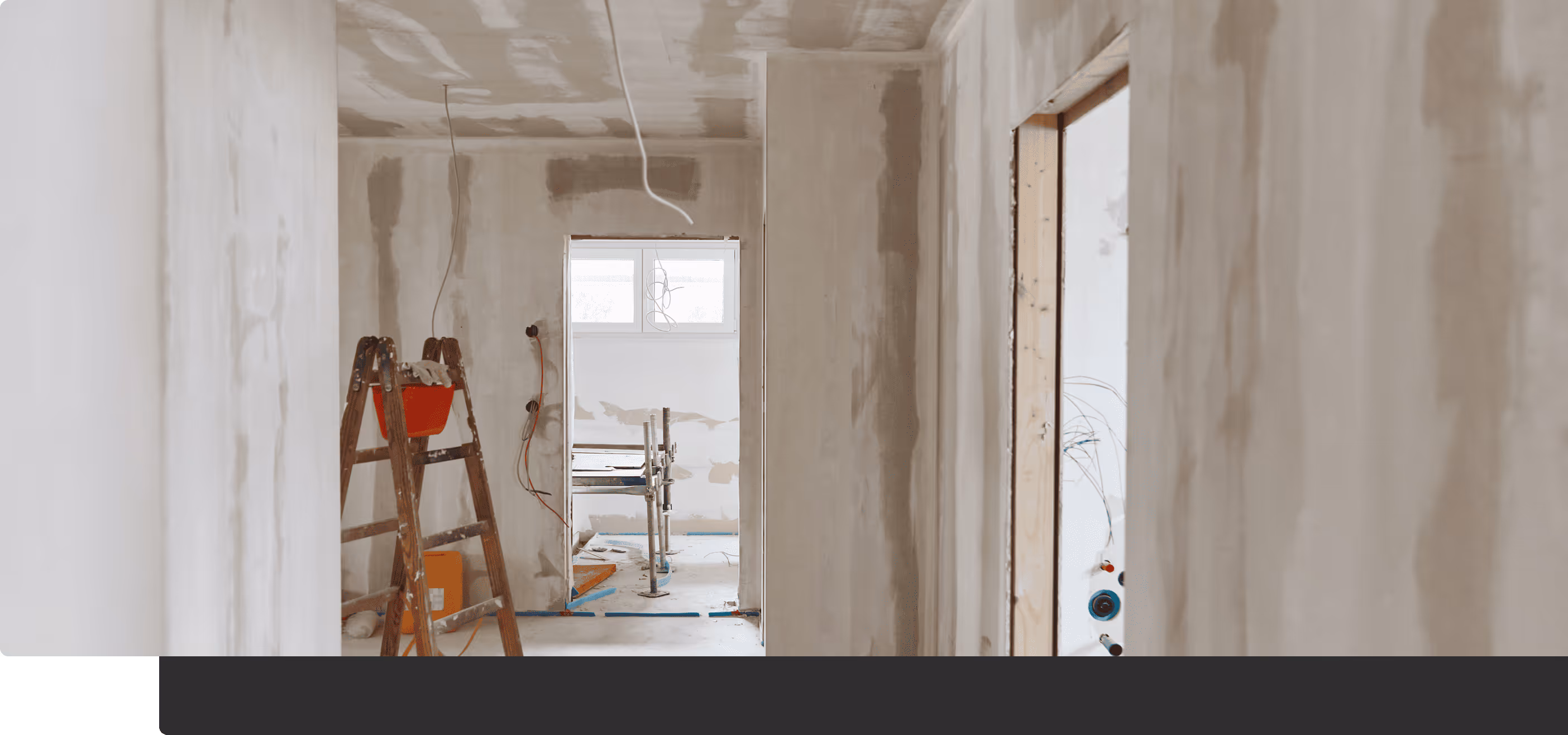 Innenraum einer Wohnung im Rohbau mit unvollständigen Wänden, einer Holzleiter und freiliegenden Kabeln.