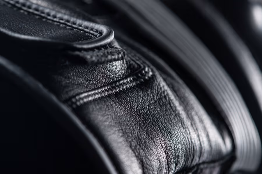 Close-up of black textured leather material with detailed stitching and a curved seam.