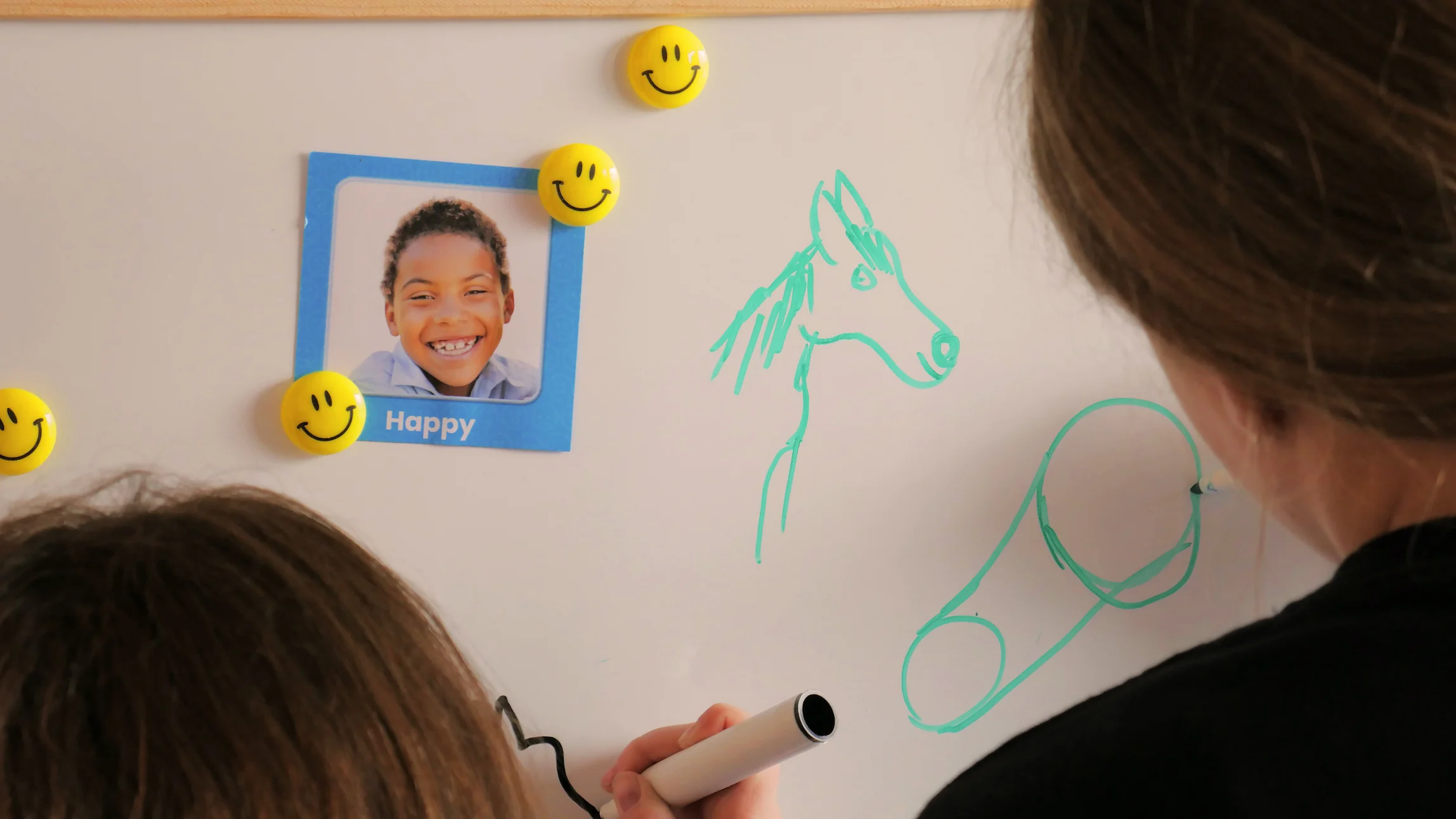 Two girls and a woman smiling and engaging in an outdoor activity near shipping containers and traffic cones.